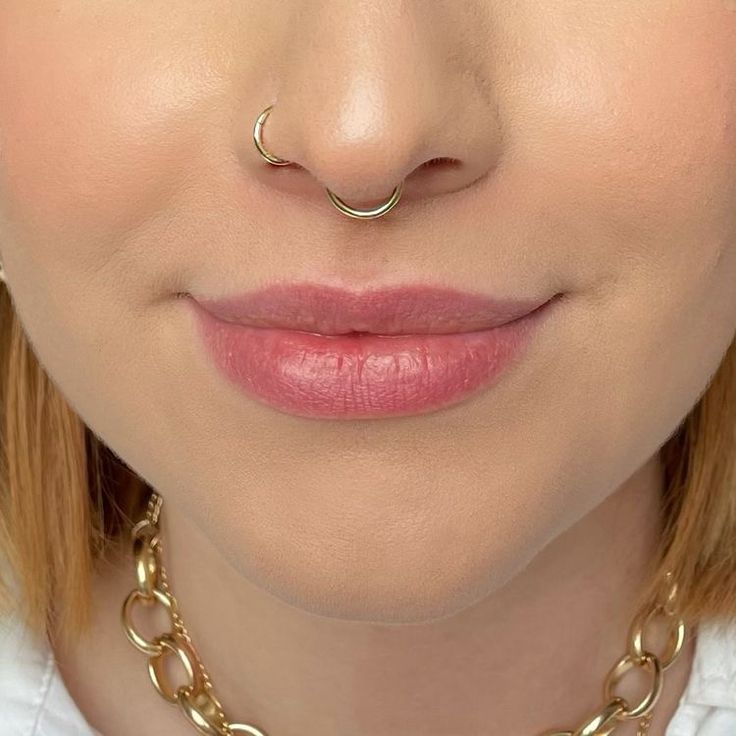 a woman wearing a gold chain necklace and nose ring