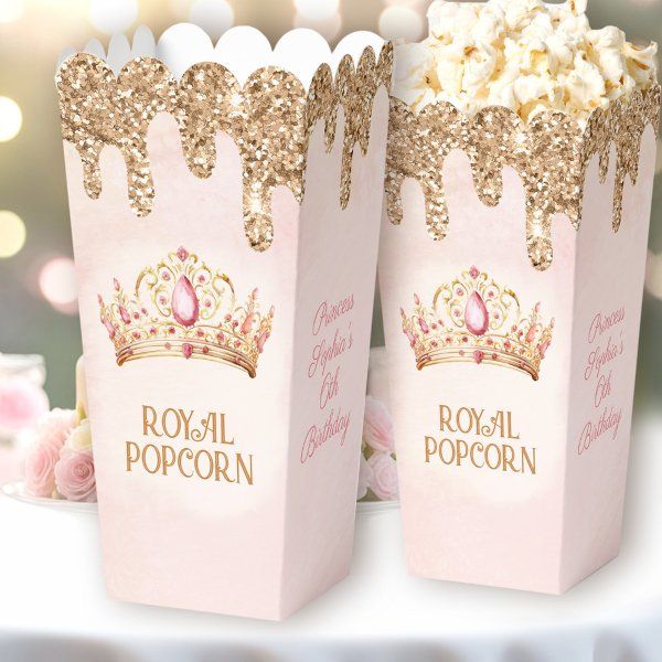 two pink popcorn boxes with gold glitter crowns on them