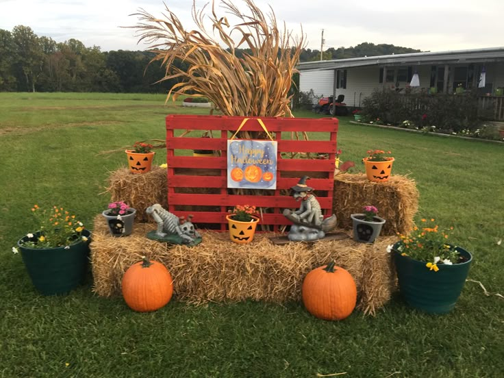 a hay bale with pumpkins and decorations on it sitting in the middle of a yard