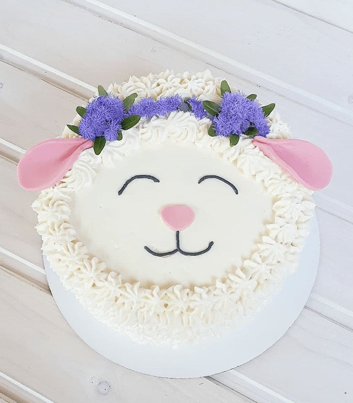 a white cake decorated with purple flowers and a sheep's head on top of it