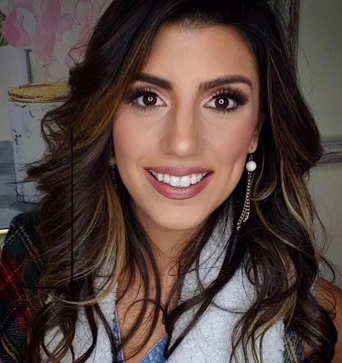 a woman with long dark hair wearing a blue tie and white shirt smiling at the camera