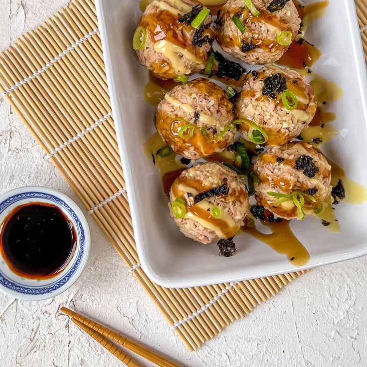 some food is sitting on a plate with chopsticks next to it