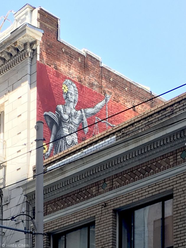 a large mural on the side of a building in front of a street light and traffic signal