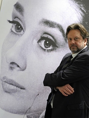 a man standing in front of a large poster with a woman's face on it