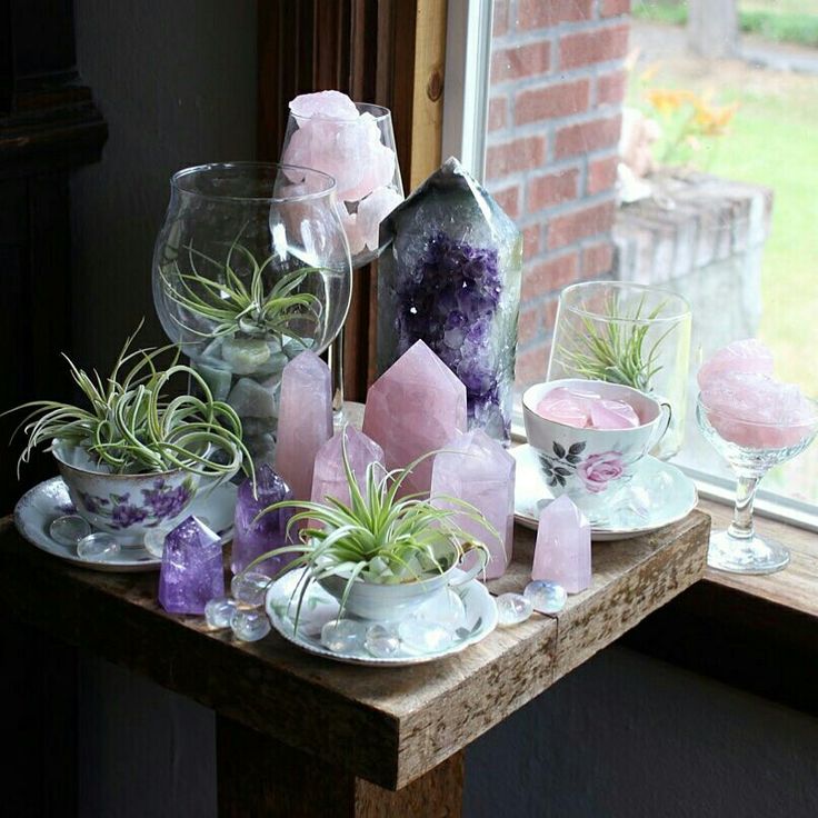 some glass vases filled with air plants and rocks on a table near a window