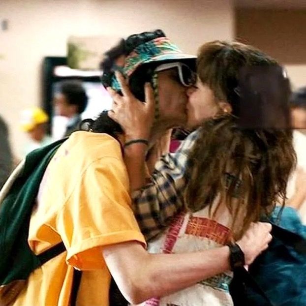 a man and woman kissing each other while standing next to each other in an airport