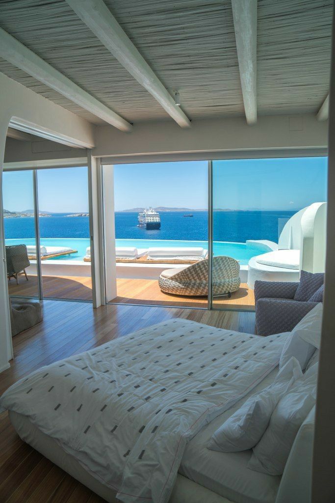 a large bed sitting in a bedroom next to an open window with a view of the ocean