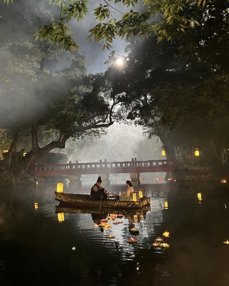 two people in a small boat on a river at night with lanterns hanging from the trees