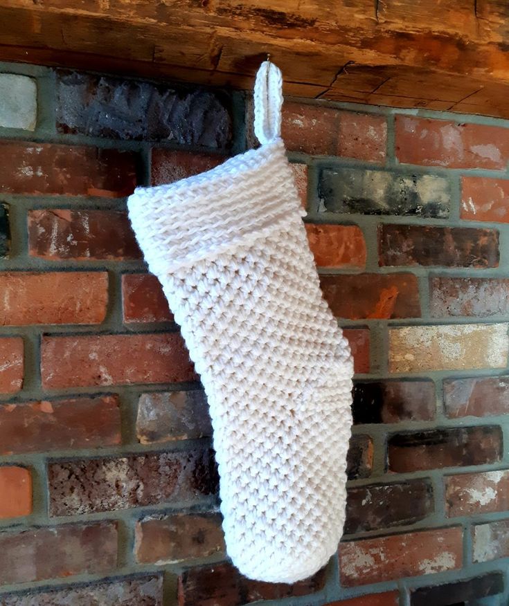 a knitted christmas stocking hanging on a brick wall