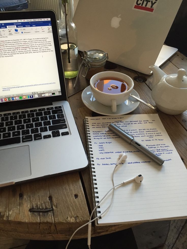 an open laptop computer sitting on top of a wooden table next to a cup of coffee