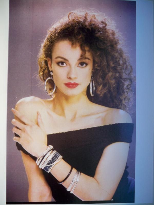 an old photo of a woman with large hoop earrings on her left arm, wearing a black off the shoulder top