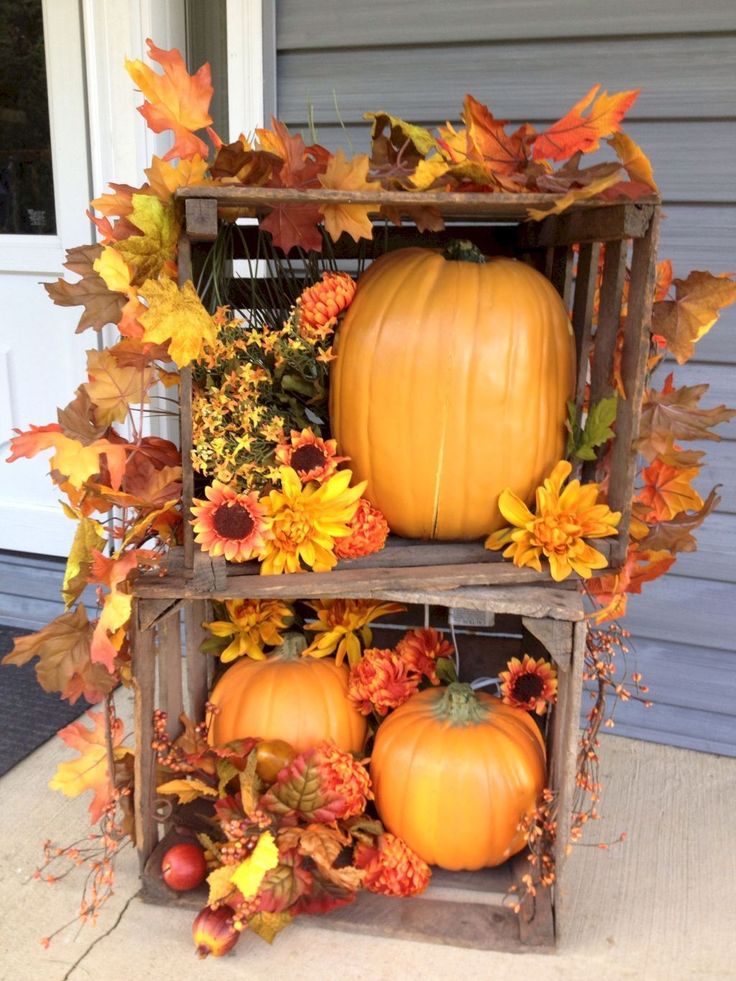 two wooden crates filled with pumpkins and autumn leaves on the front porch in fall