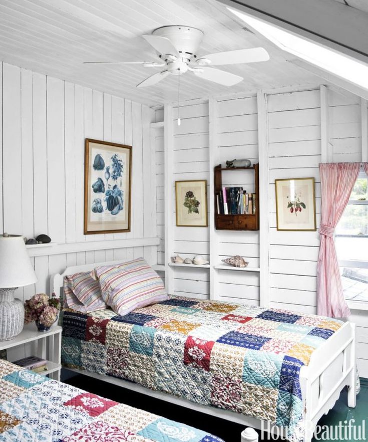 two beds in a room with white walls and blue carpeted flooring, one has a colorful quilt on the bed