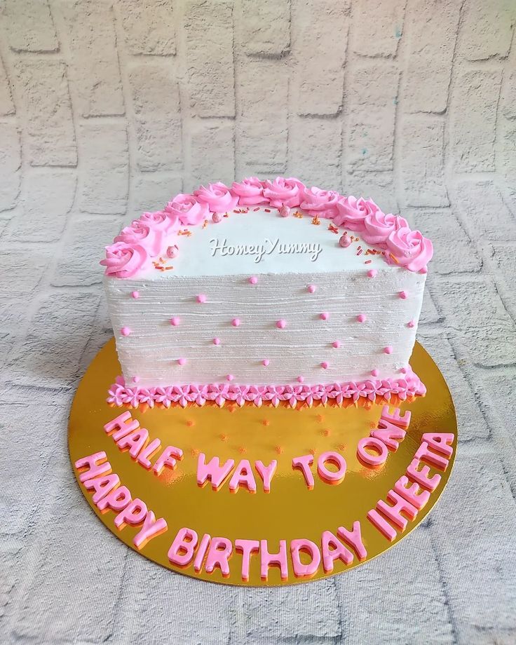 a birthday cake with pink frosting on a gold plate