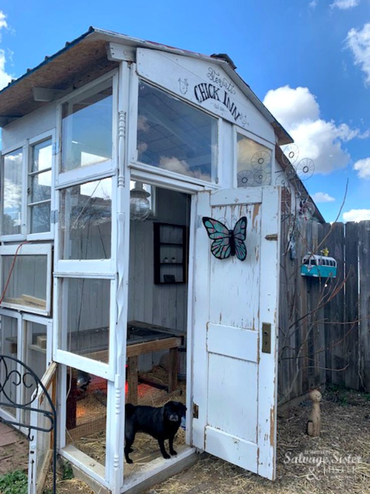 an old outhouse with a black dog in the doorway and a butterfly on the door