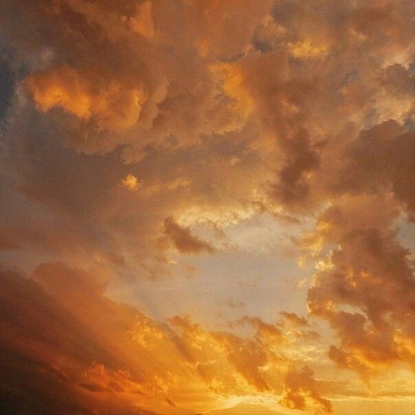 an airplane is flying in the sky with clouds above it at sunset or sunrise time