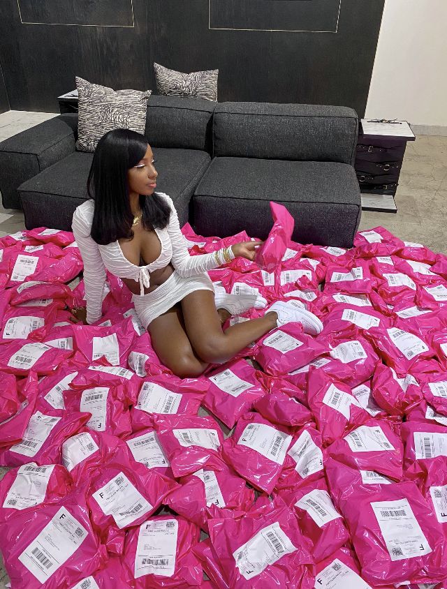 a woman sitting on the floor surrounded by pink bags