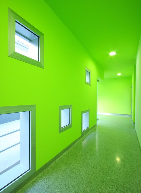 an empty hallway with green walls and windows