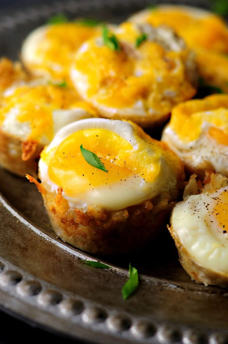 an egg and cheese muffins are on a metal platter with green garnish