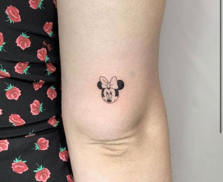 a woman's arm with a small mickey mouse tattoo on the left side of her right arm