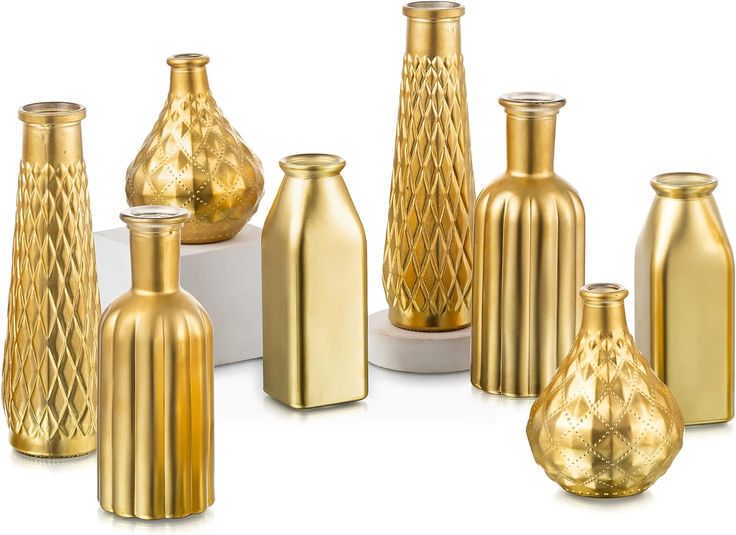 a group of gold vases sitting next to each other on a white table top