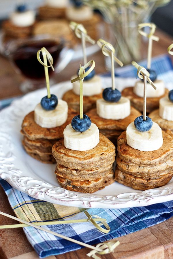 some pancakes with blueberries and cream on top are arranged on a white platter