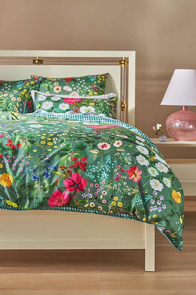 a bed with green and pink flowers on the comforter is shown in this image