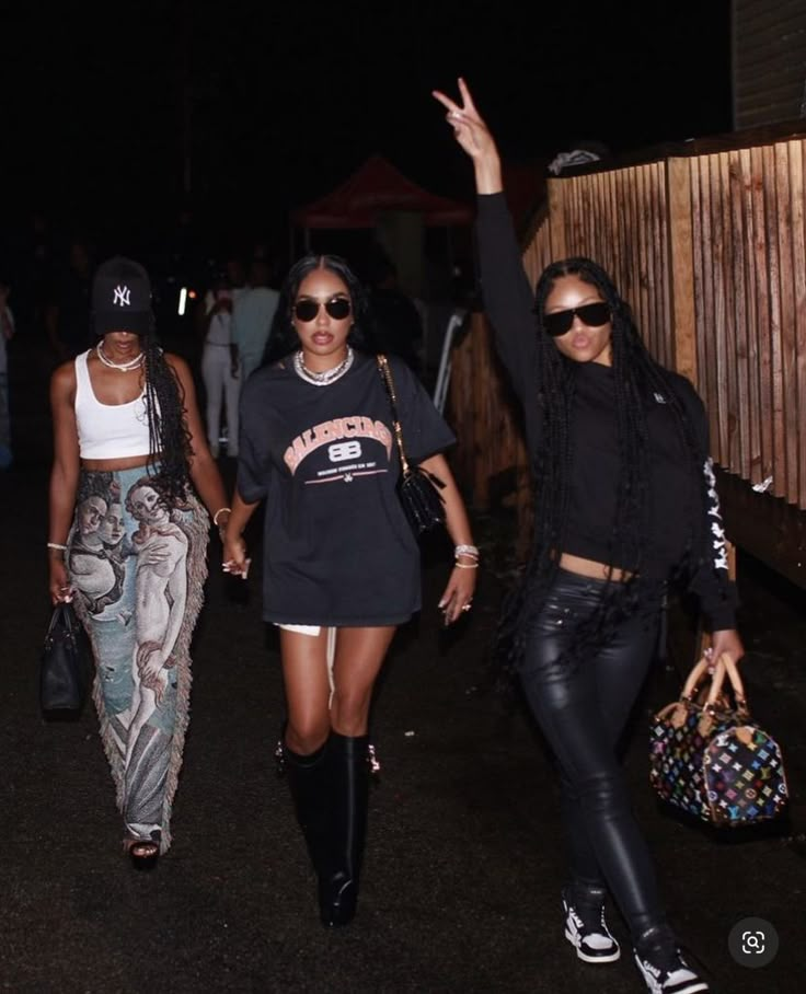 three women walking down the street at night with one holding her hand up in the air