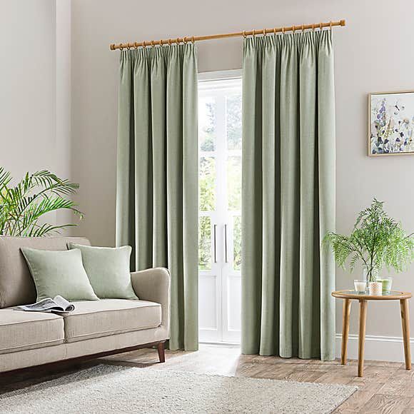 a living room with a couch, chair and window covered in light green drapes