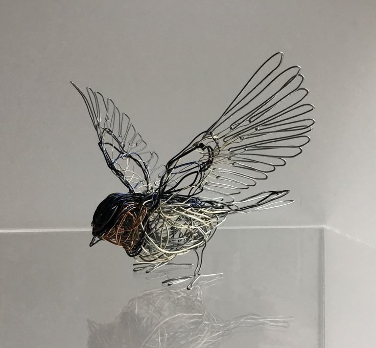 a wire bird sculpture sitting on top of a glass shelf next to a white wall