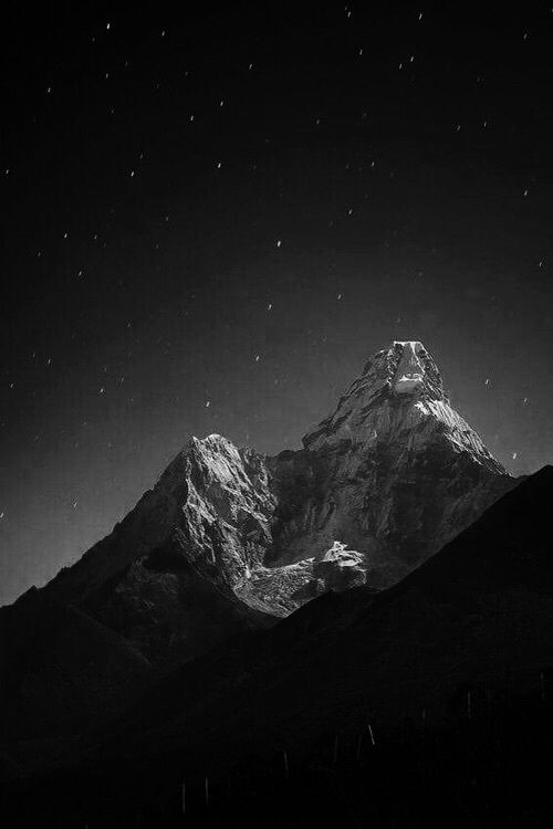 black and white photograph of the top of a mountain at night with stars in the sky