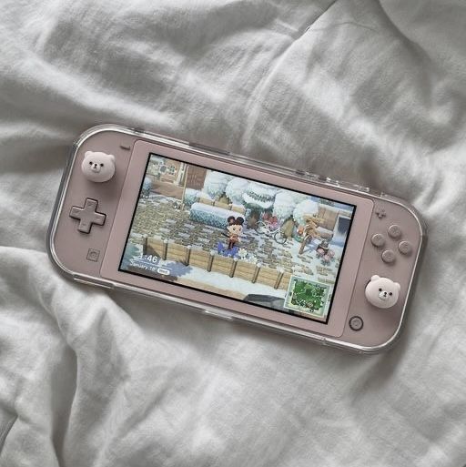 a nintendo wii game system sitting on top of a bed covered in white linens