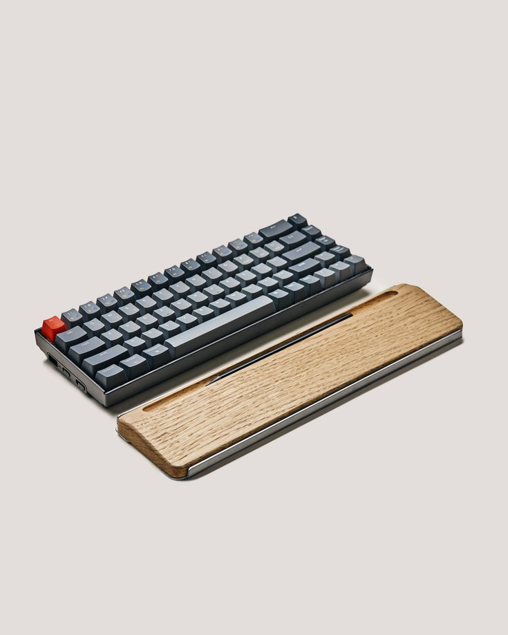 a computer keyboard sitting on top of a wooden mouse pad with a black and red key board