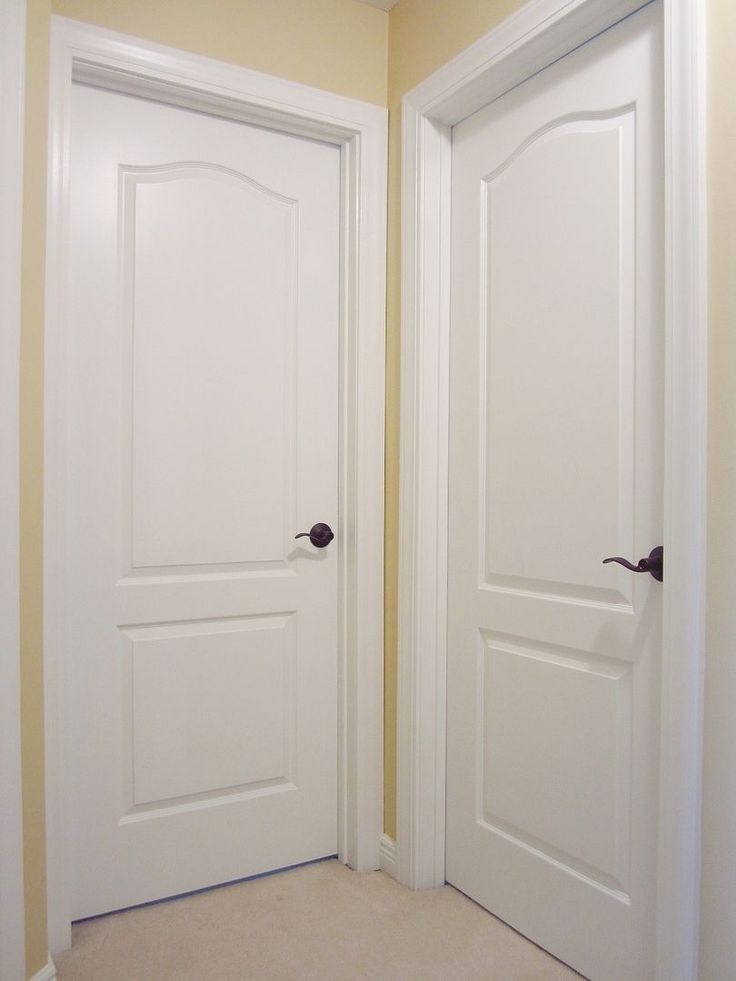 two white doors are open in the corner of a room with carpeted flooring