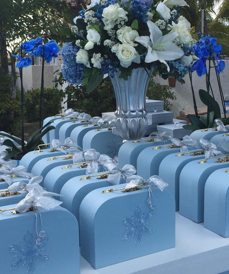 many blue boxes with white flowers in them are on display at a wedding or other event