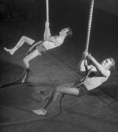 two men are performing aerial acrobatic tricks on the ropes in an old black and white photo