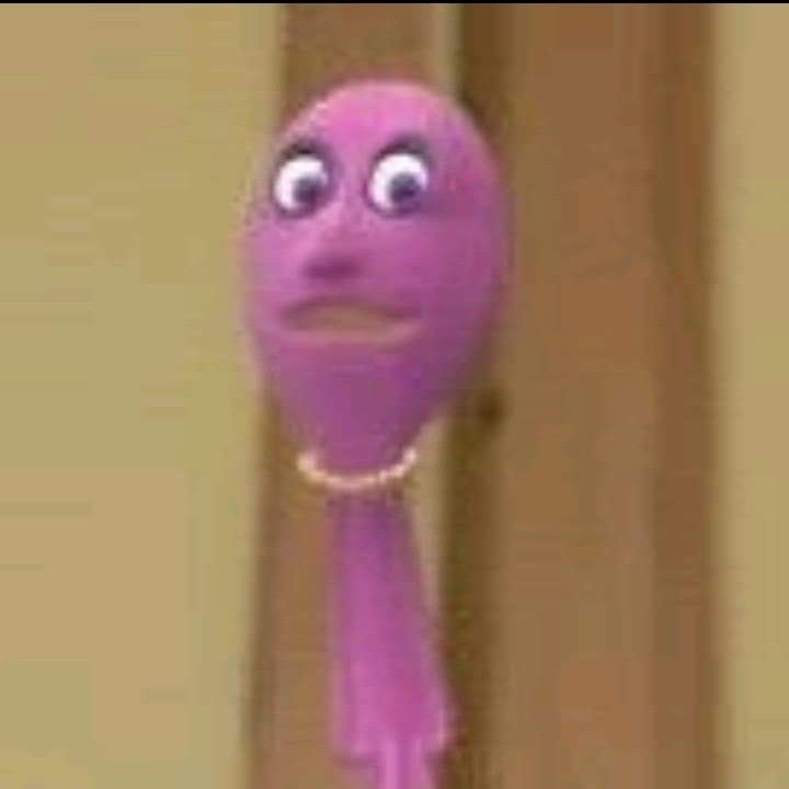 a purple toy with eyes and a chain around it's neck is standing in front of a door