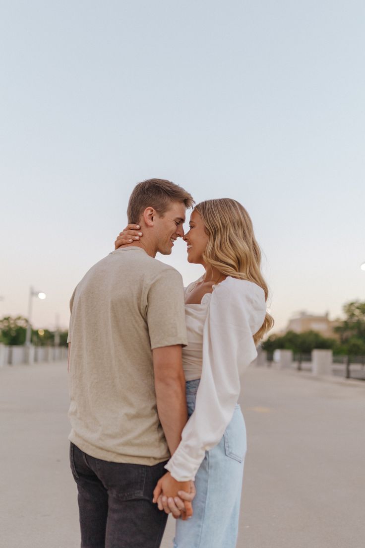 a man and woman holding hands in the middle of an empty parking lot at sunset