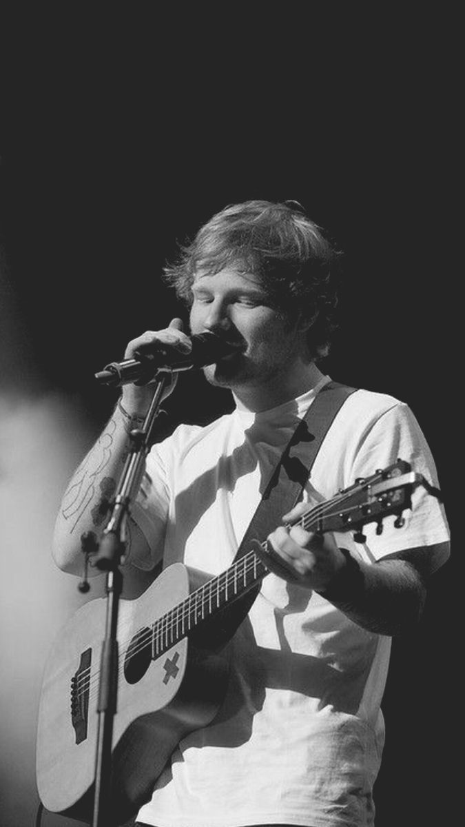 a man holding a guitar and singing into a microphone