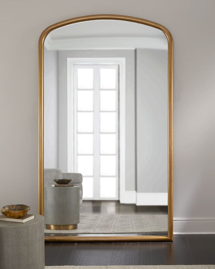 a large gold framed mirror sitting on top of a wooden floor next to a white door