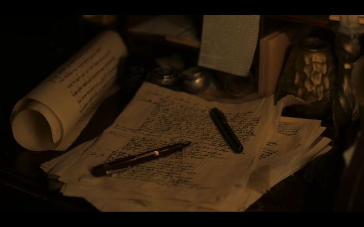 an open book with writing on it next to a pen and some other items in the background