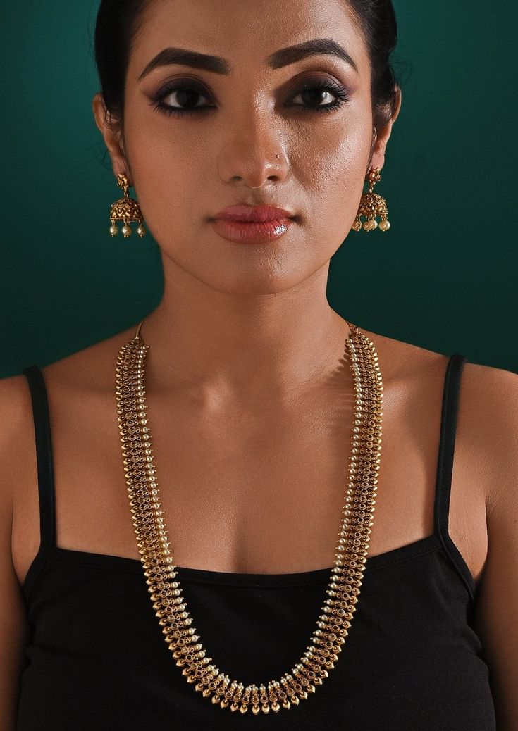 This elegant Antique Gold Plated Long Necklace Set features a beautifully crafted layered necklace paired with matching earrings. The necklace's intricate design and the earrings’ delicate detailing make it perfect for traditional or formal occasions. Ideal for adding a touch of sophistication to any outfit, this set is a timeless addition to your collection. The necklace measures by 38 inches, and earrings by 4.5 inches in lengthComposition : Mixed Metal with other Semi Precious StonesCare: Keep away from water and perfume Delivery : 2-4 weeks as the product is hand crafted. For more information and sizes please contact fabiliciousfashion@gmail.com or visit our Copenhagen studio. About the Designer : Zaza by Somya is a thoughtfully curated collection of bold yet feminine jewelry pieces. H Formal Temple Jewelry Kundan Necklace With Matching Earrings, Elegant Gold Dual-tone Kundan Necklace, Elegant Dual-tone Kundan Necklace For Wedding, Temple Jewelry Sets With Matching Earrings For Formal Occasions, Elegant Cutdana Jewelry Sets For Party, Elegant Temple Necklace With Matching Earrings, Elegant Cutdana Jewelry For Parties, Elegant Festive Dual-tone Necklace, Festive Elegant Dual-tone Necklace