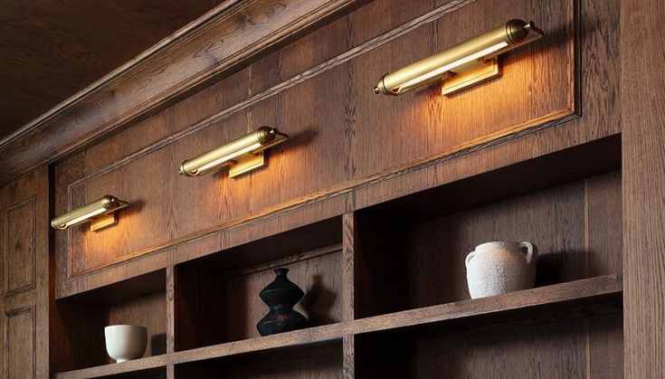 a wooden bookcase with three lights on each side and two vases in the middle