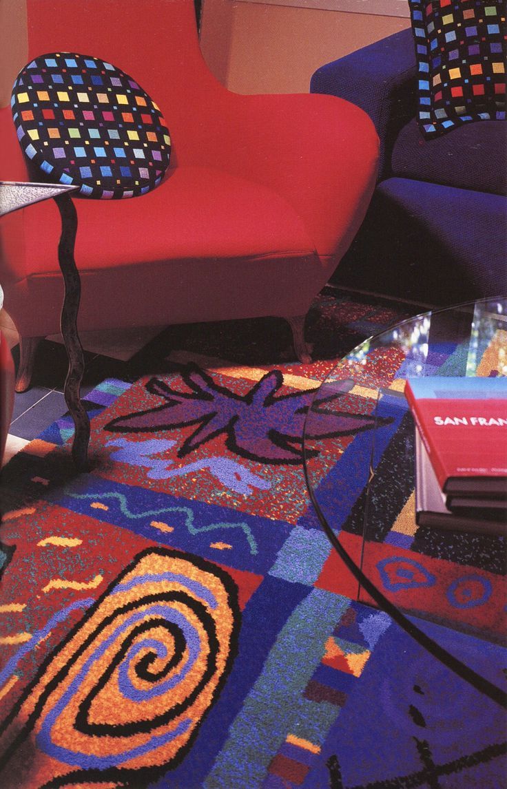 a living room with two colorful chairs and a book on the floor in front of it