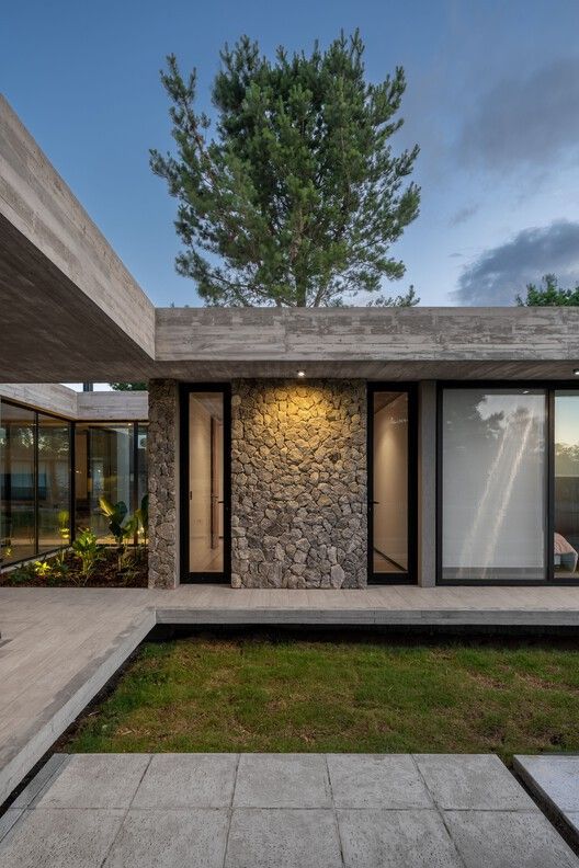 the exterior of a modern house with stone and glass