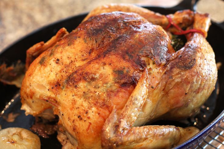 a whole chicken sitting on top of a white plate next to a bottle of wine