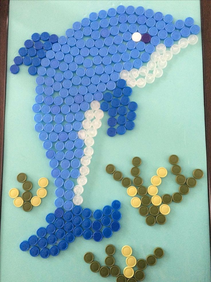 a blue and white dolphin made out of plastic bottle caps with the word love spelled below it