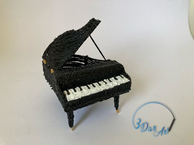 a miniature piano made out of yarn on a white surface with the word sparkle written below it