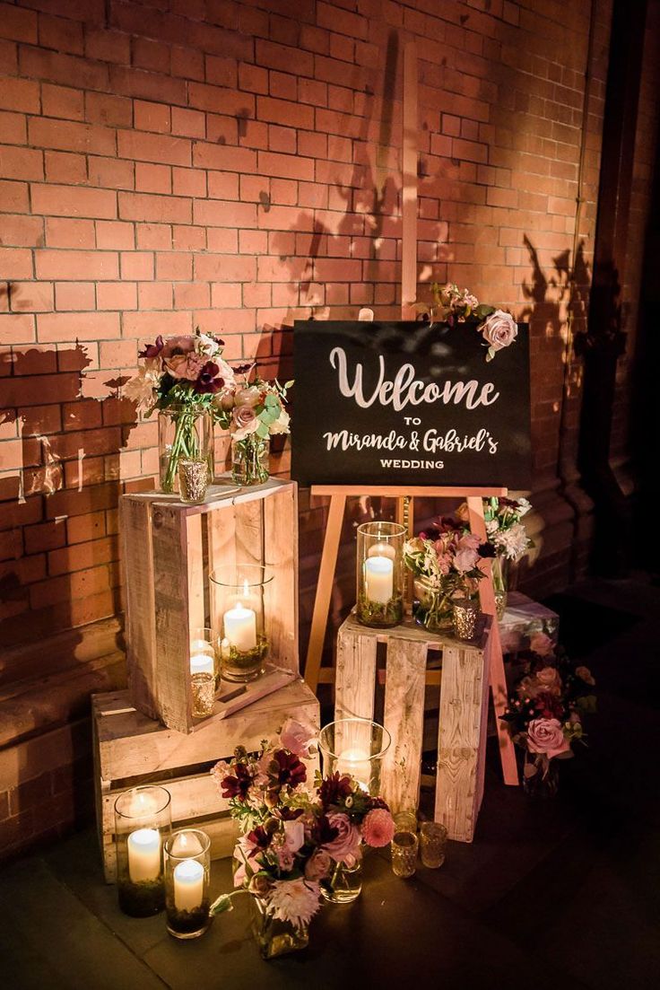 the welcome sign is surrounded by wooden crates and lit candles in front of a brick wall