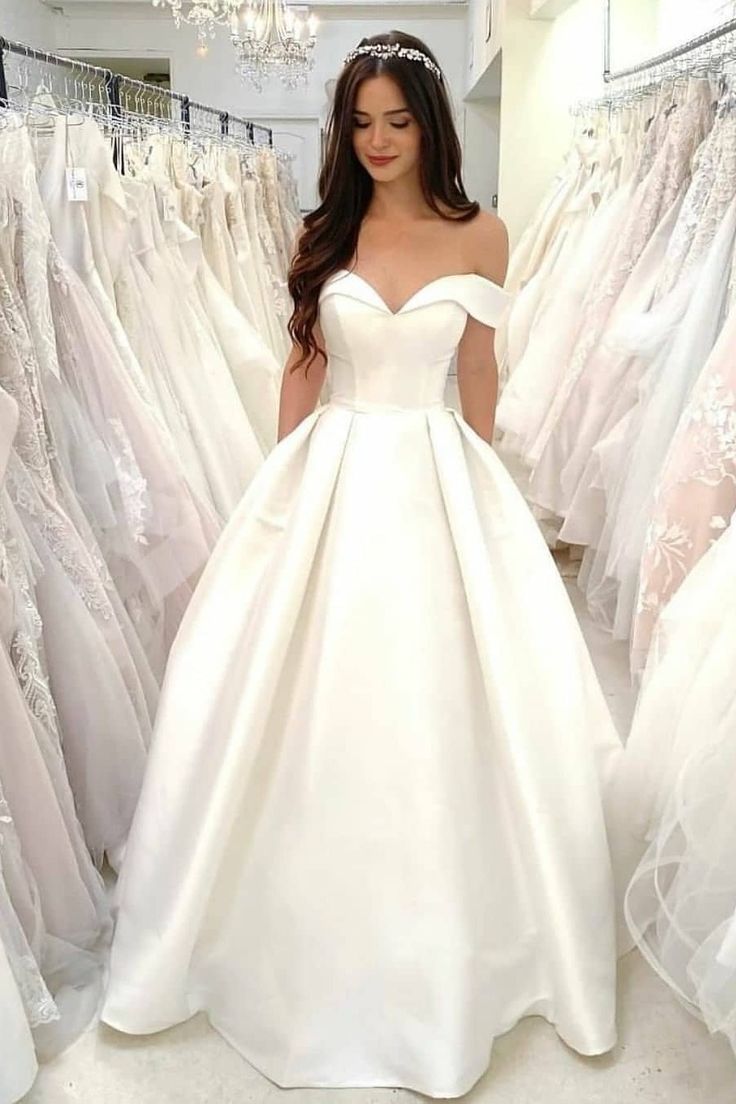 a woman is standing in front of some wedding dresses